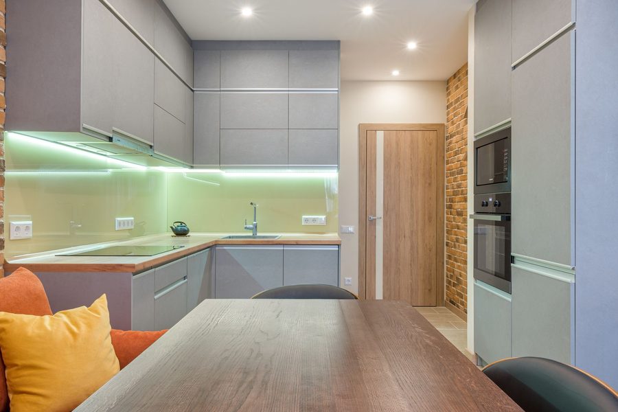 Exposed red brick accent wall in a modern kitchen beside grey cabinets