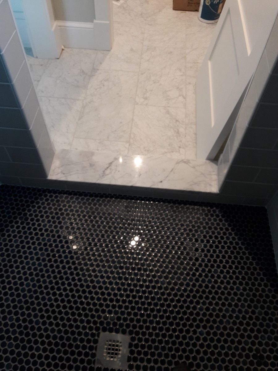 Marble threshold finishing the edge where a tiled shower floor meets the bathroom floor
