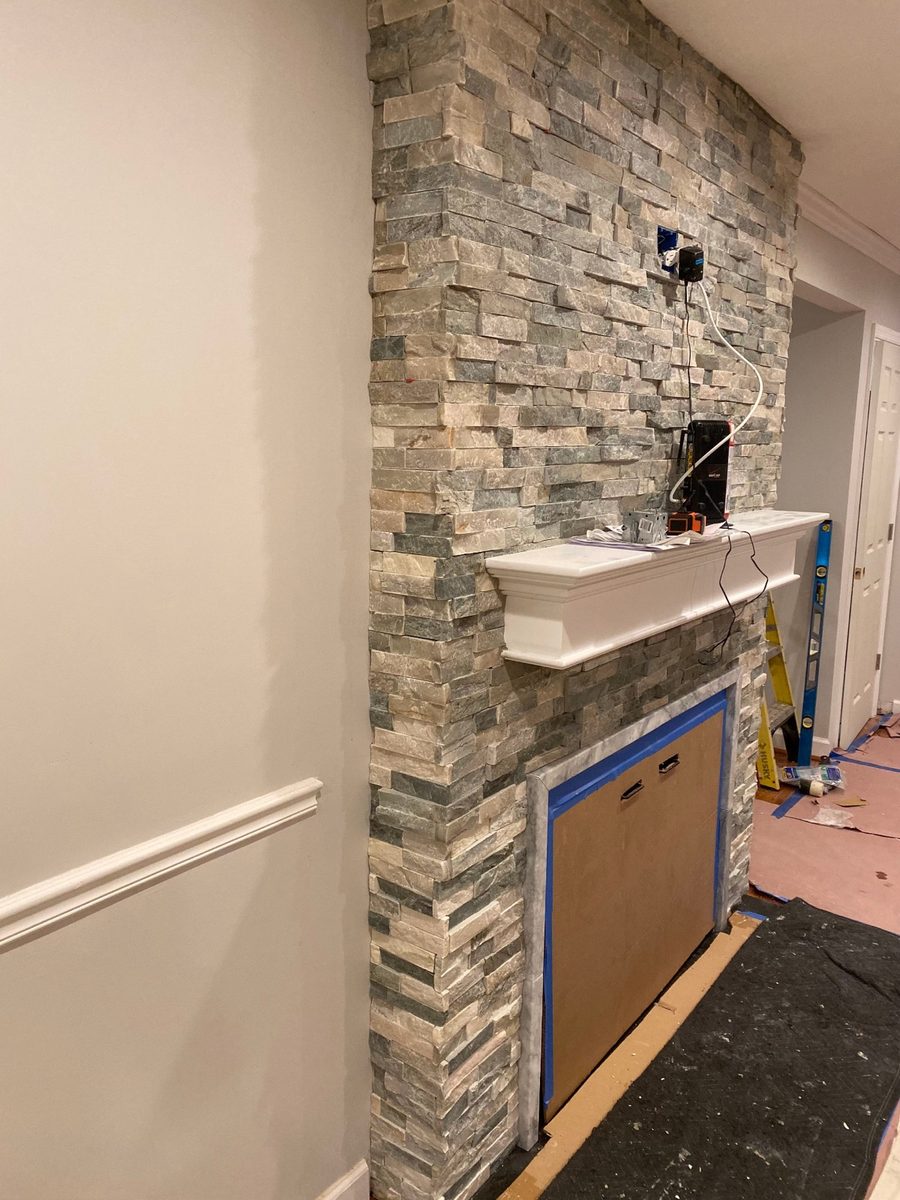 Stone veneer fireplace surround going up over a flattened wall during installation