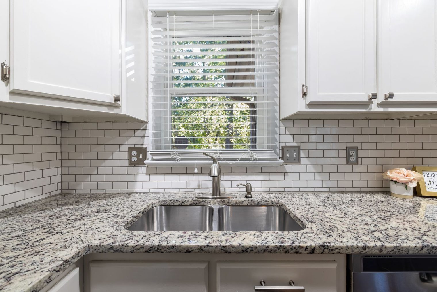 White subway tile kitchen backsplash with dark grout above a granite countertop, outlets set into the tile