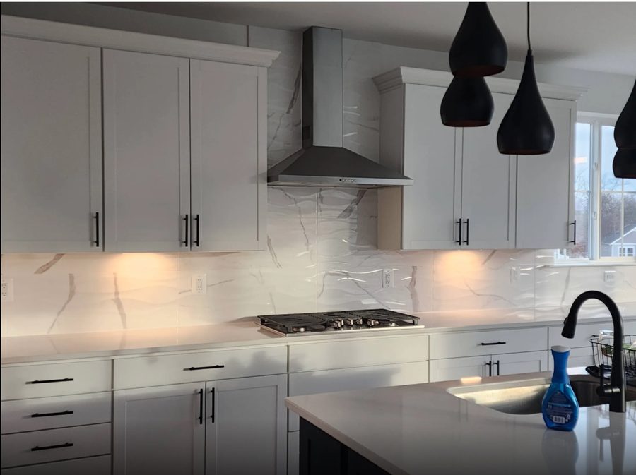 Kitchen backsplash in white marble-look tile running up to a stainless steel range hood