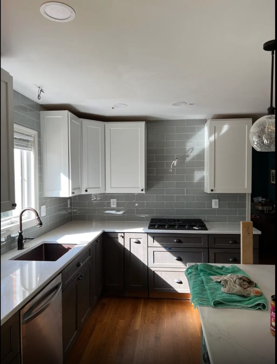 Grey glass subway tile backsplash over quartz countertops in a kitchen