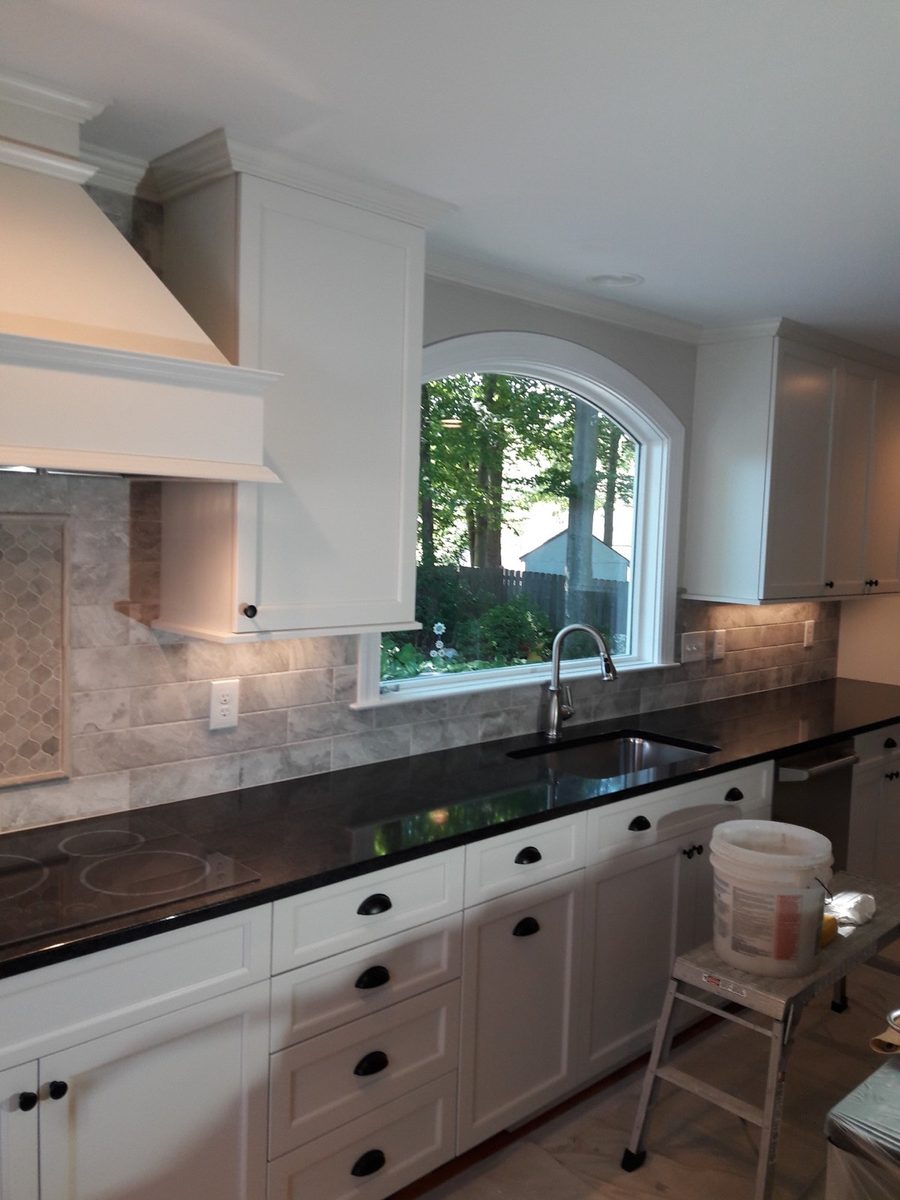Grey subway tile backsplash behind white kitchen cabinets and a quartz countertop