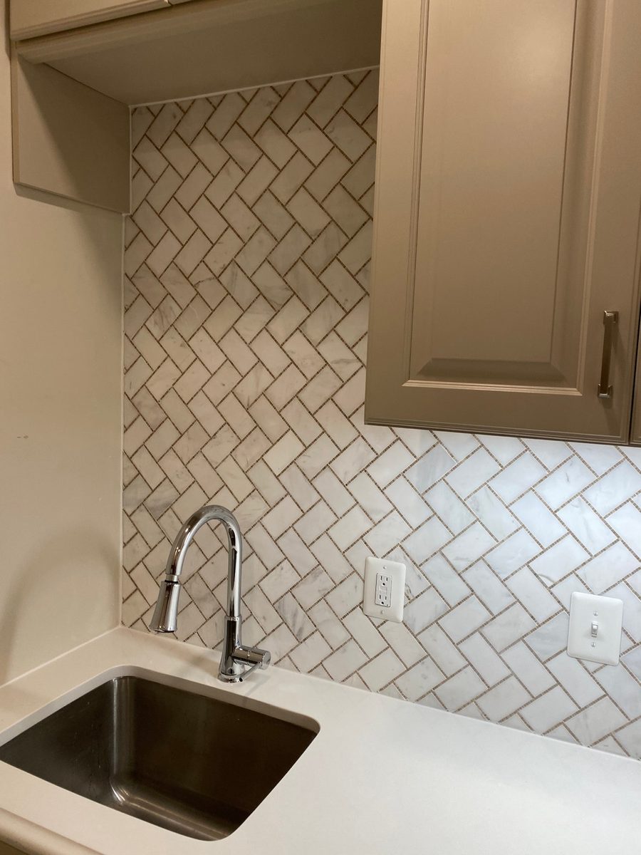 Herringbone pattern tile backsplash during installation