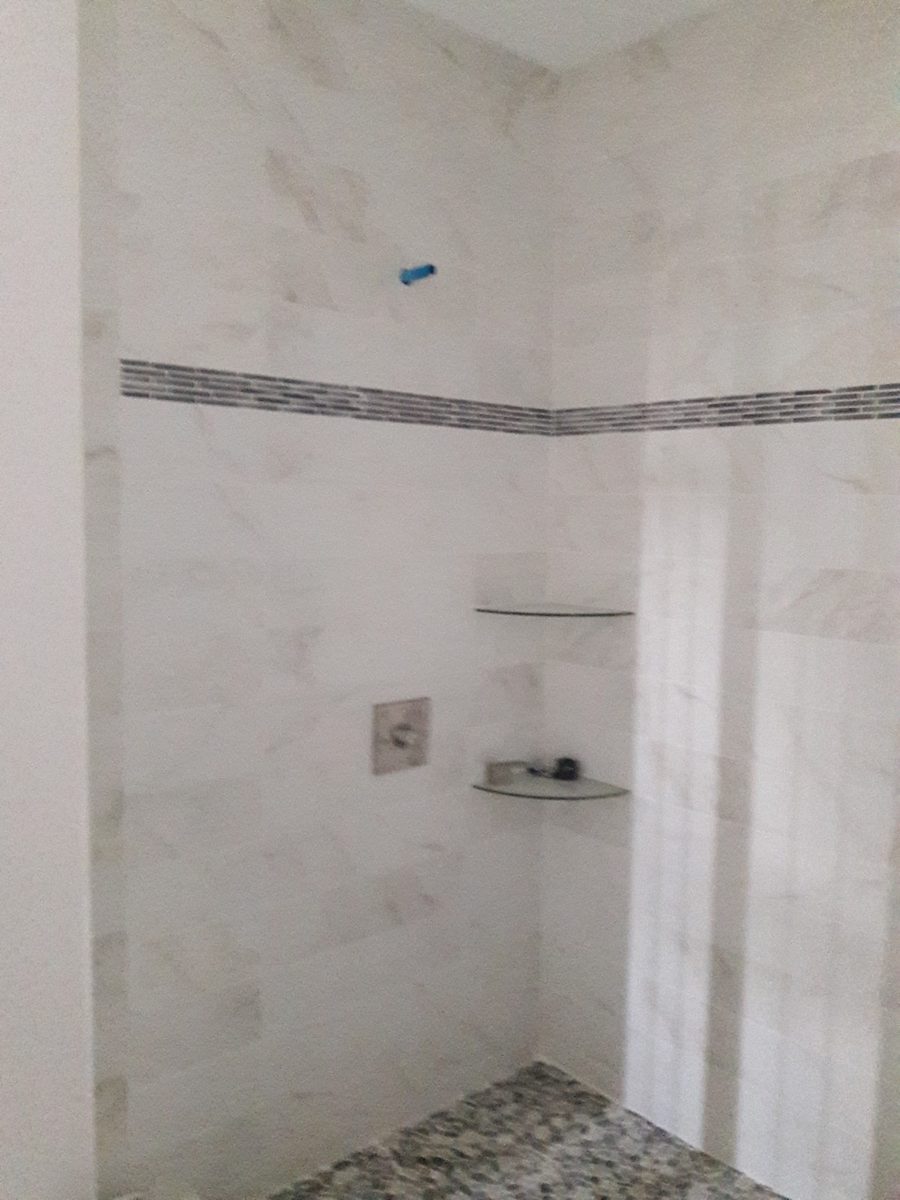 Large format white shower wall tile with a mosaic accent band