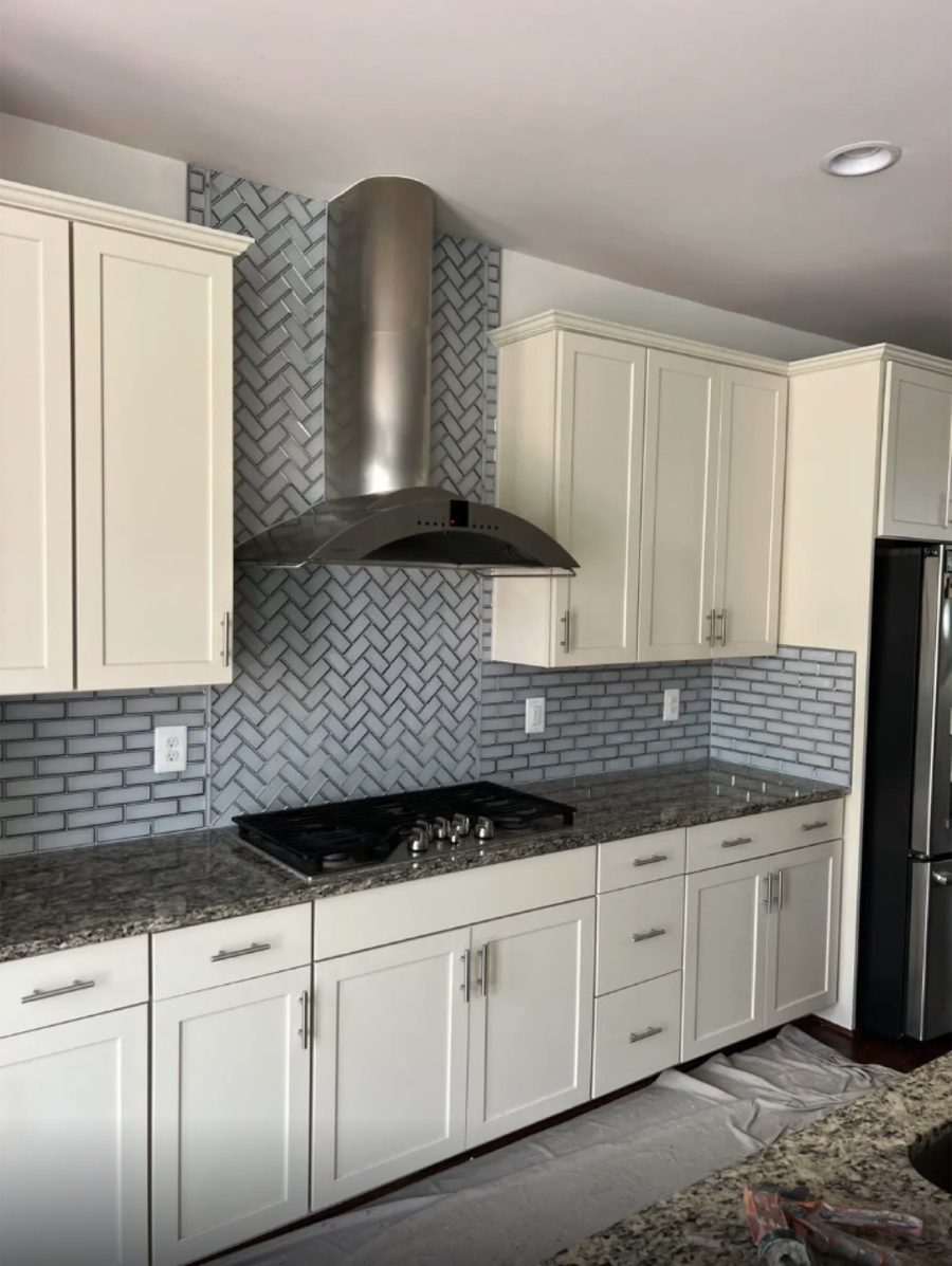 Grey herringbone tile backsplash set behind a kitchen range hood