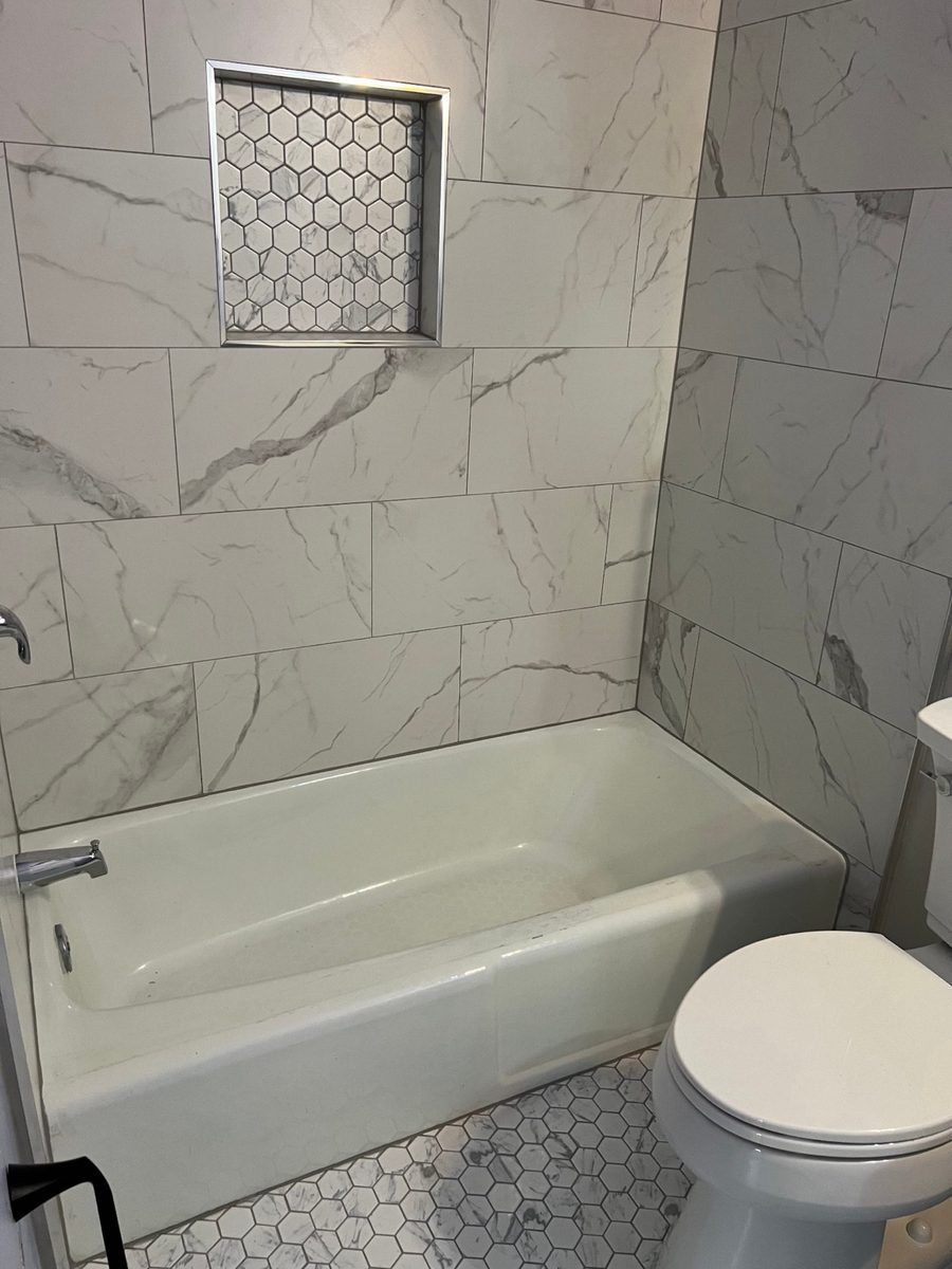 Marble tile bathtub surround with a hexagon mosaic niche by MCode
