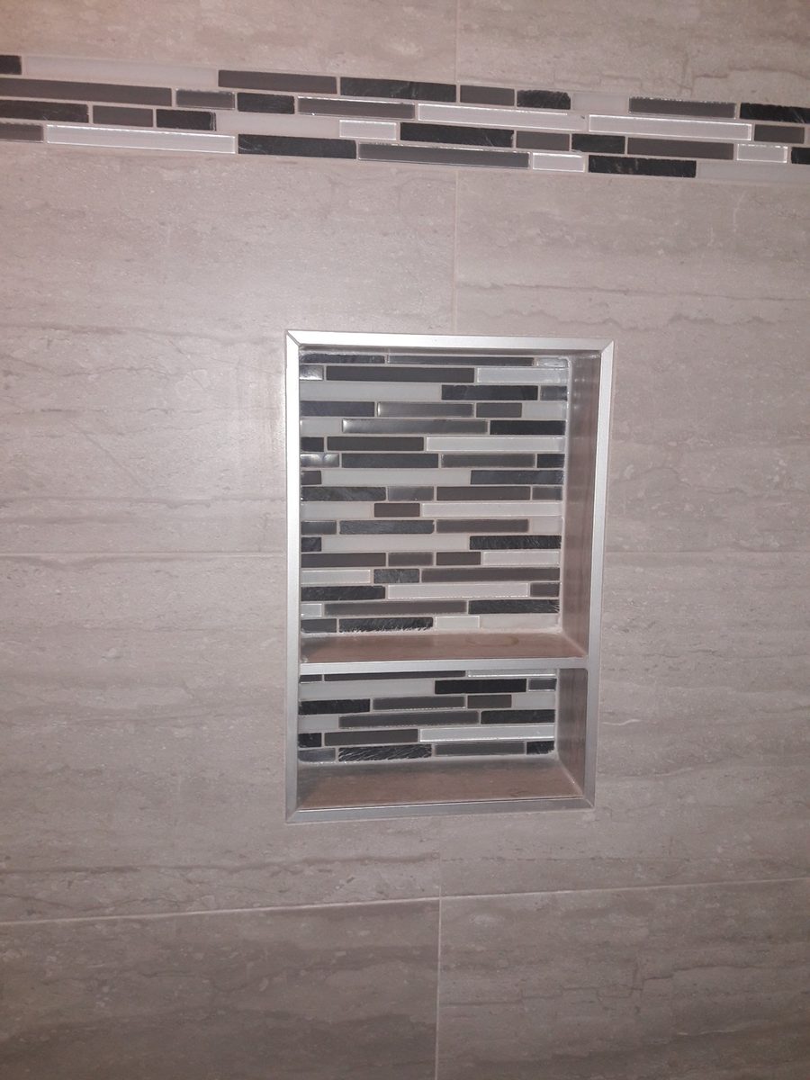 Finished glass and stone mosaic shower niche with an accent band