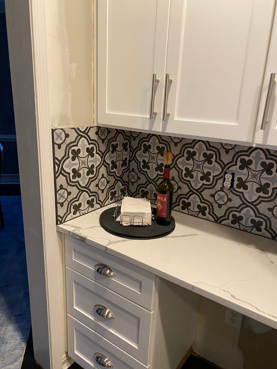 Patterned encaustic cement tile backsplash against plain cabinetry