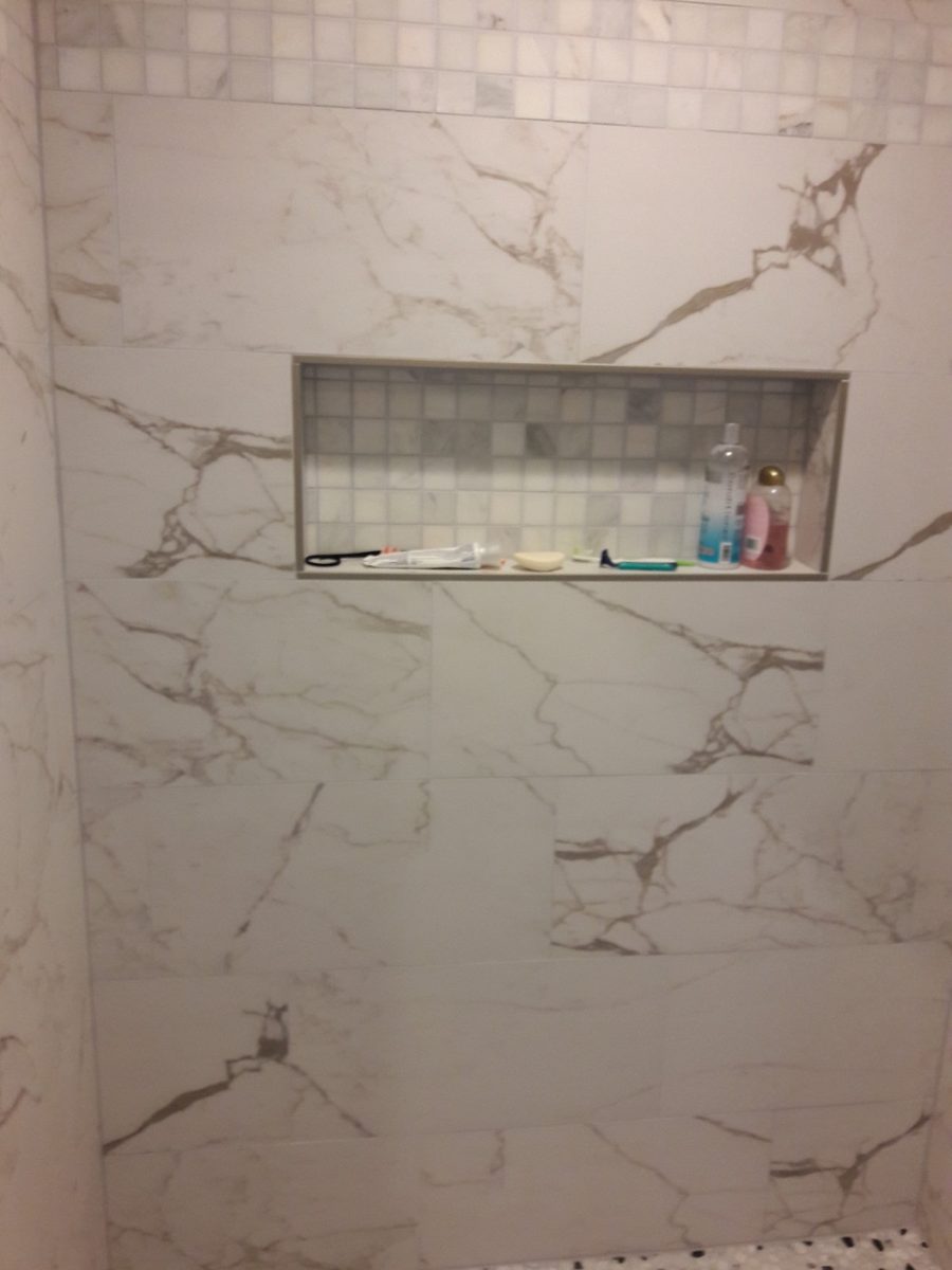 Marble look shower wall tile with a large mosaic niche