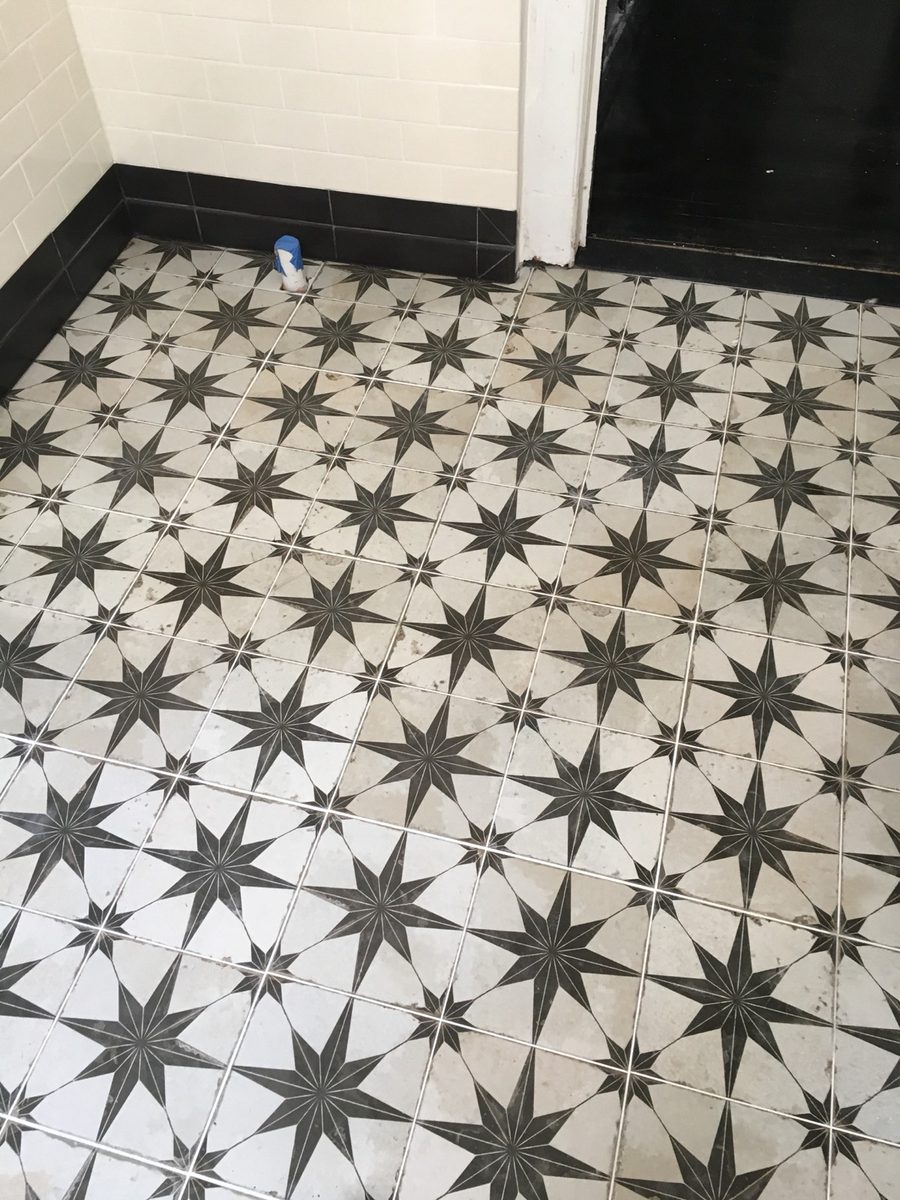 Black and white star pattern bathroom floor tile in a small bathroom