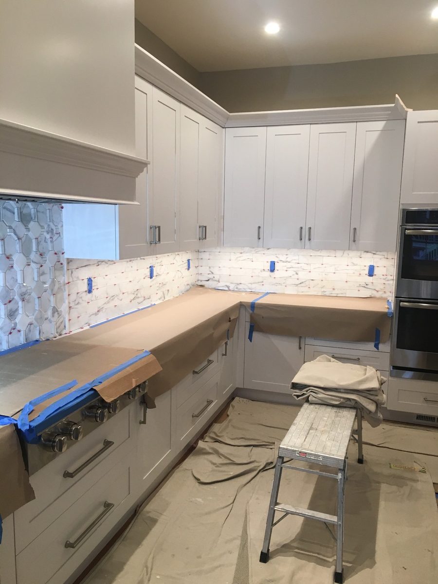 White kitchen with a marble backsplash and mosaic accent wall