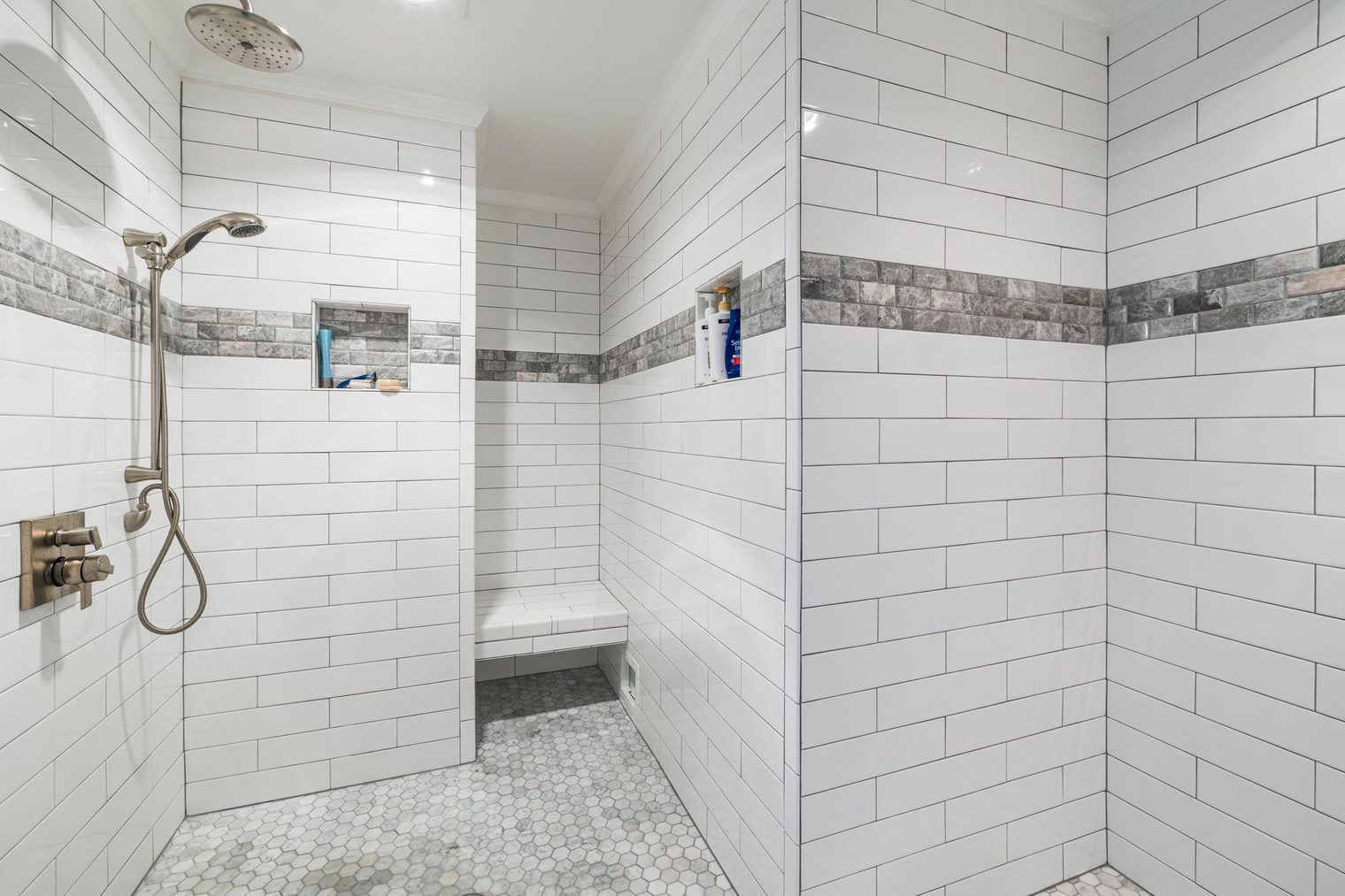 Tiled walk-in shower with a hexagon mosaic floor sloped to the drain and a built-in bench