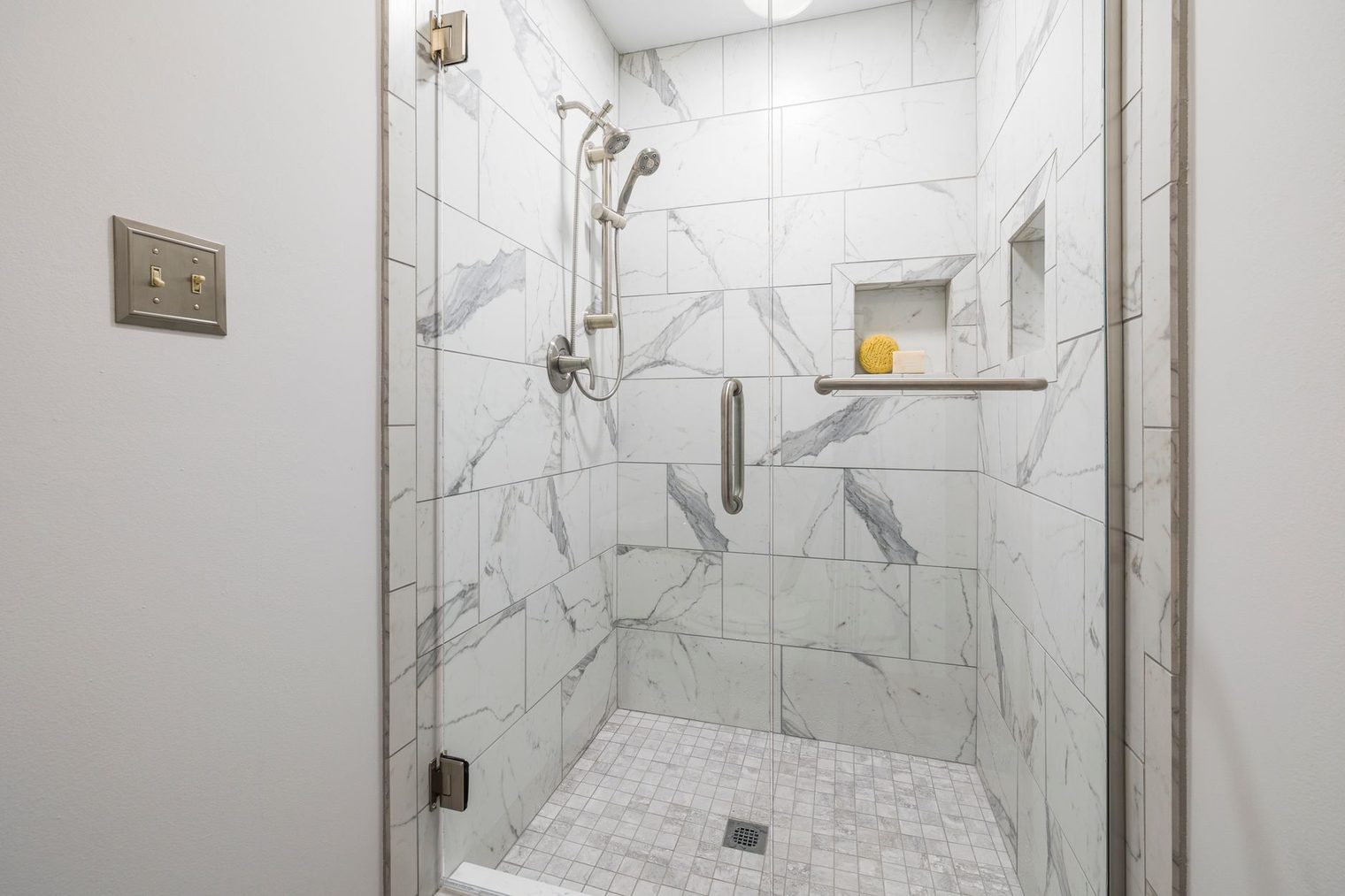 Marble tile shower with a recessed tiled niche and mosaic floor