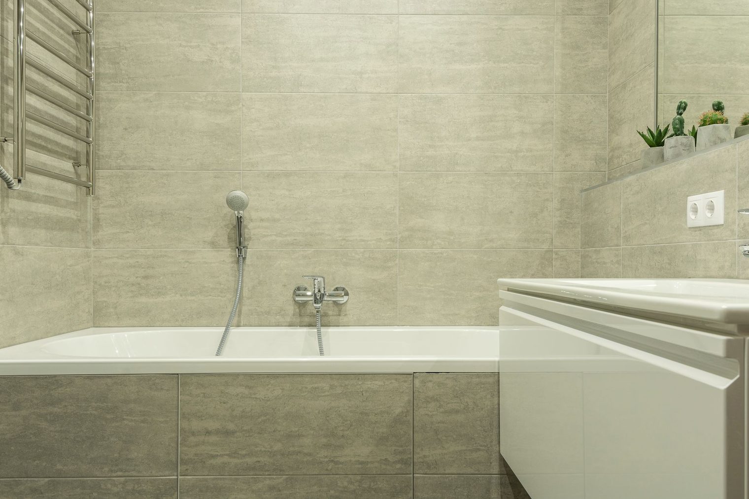 Large format tile bathtub surround with a tiled tub apron in a modern bathroom