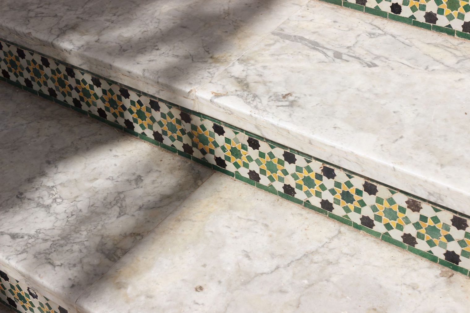 Marble stair treads with decorative mosaic tiled risers and a bullnosed step edge