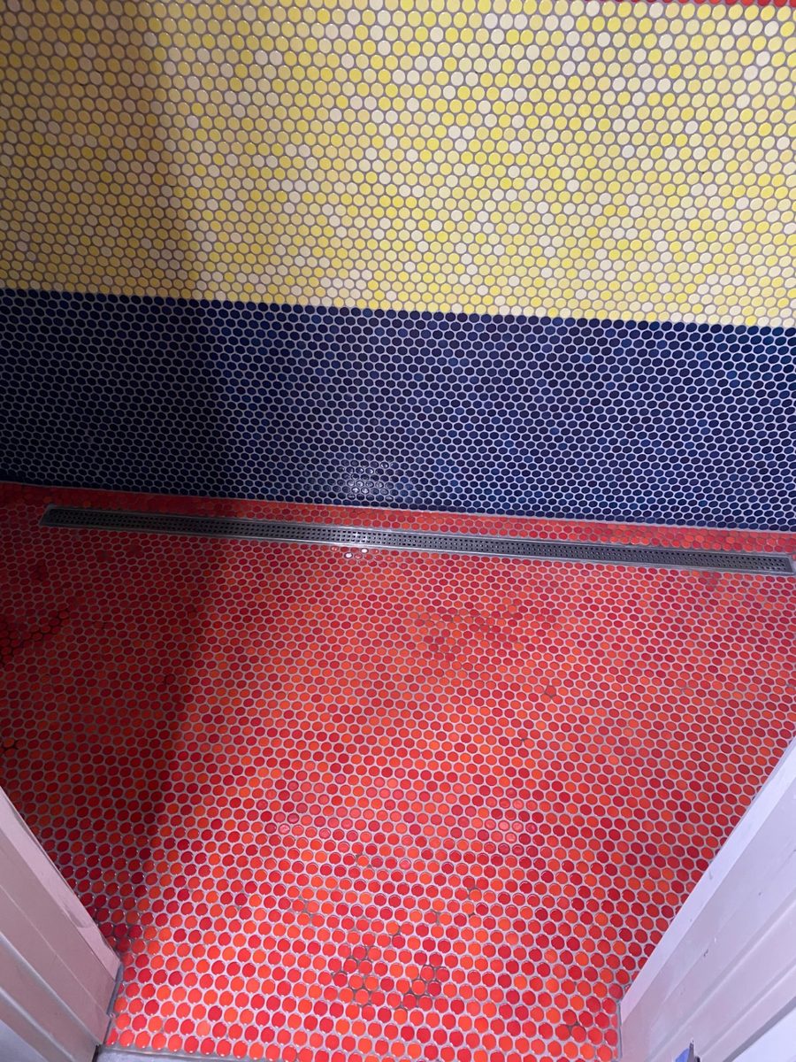Penny round mosaic shower floor sloped to a linear drain, the small tile following the slope