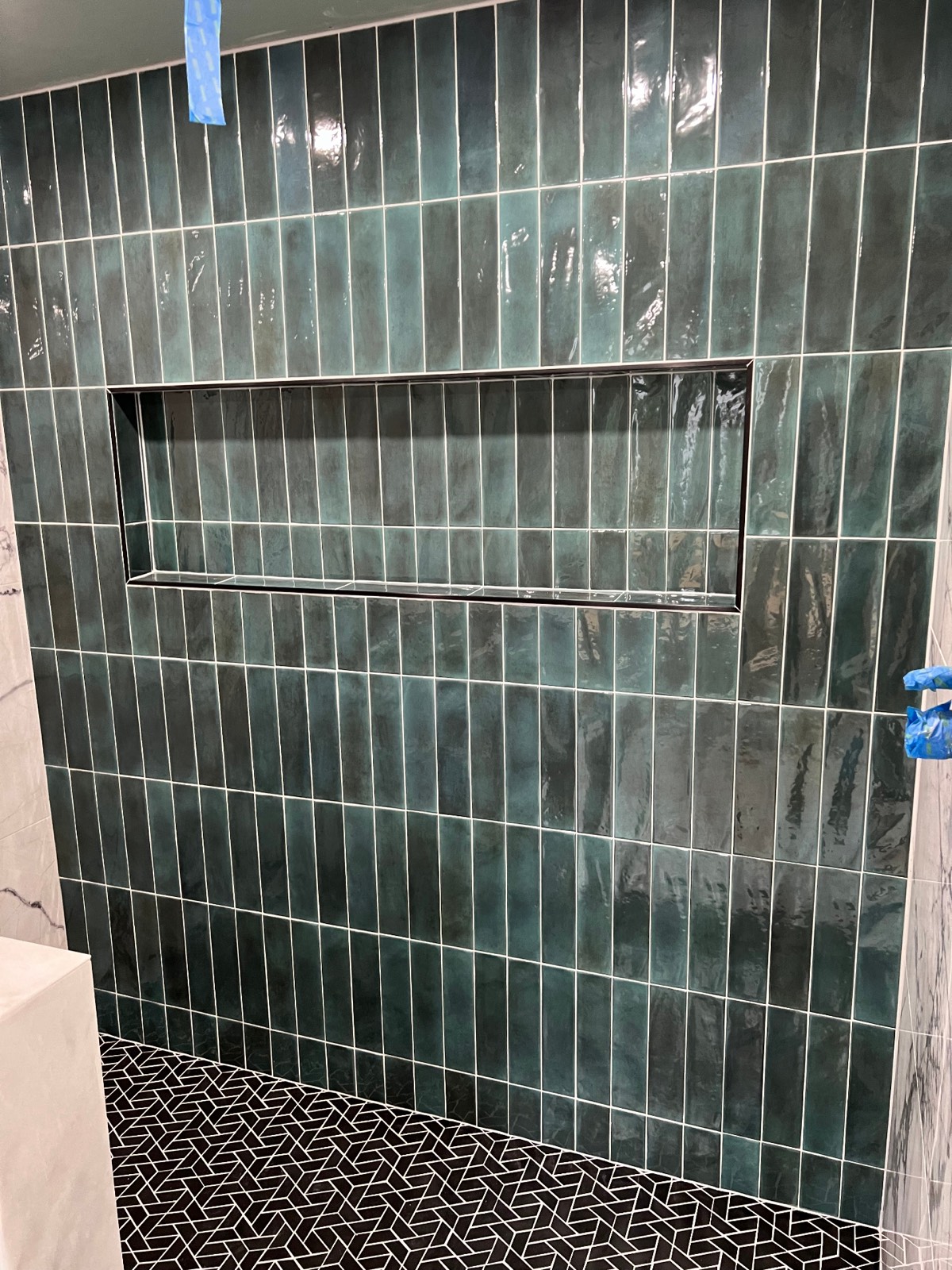 Green vertical stack subway tile on a shower wall with a full-height tiled niche