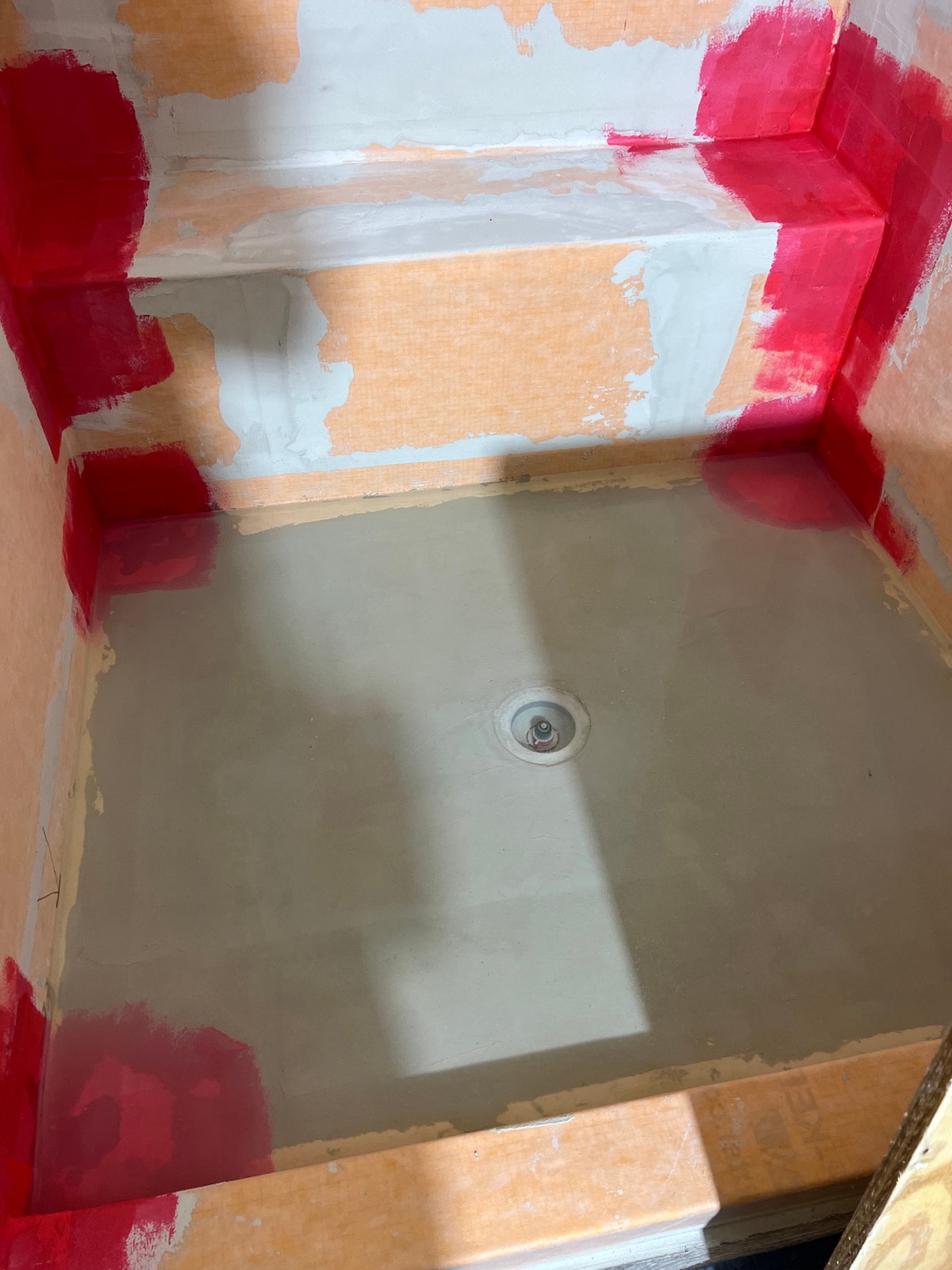 Shower waterproofing membrane bonded over the walls with lapped seams and reinforced corners, before any tile