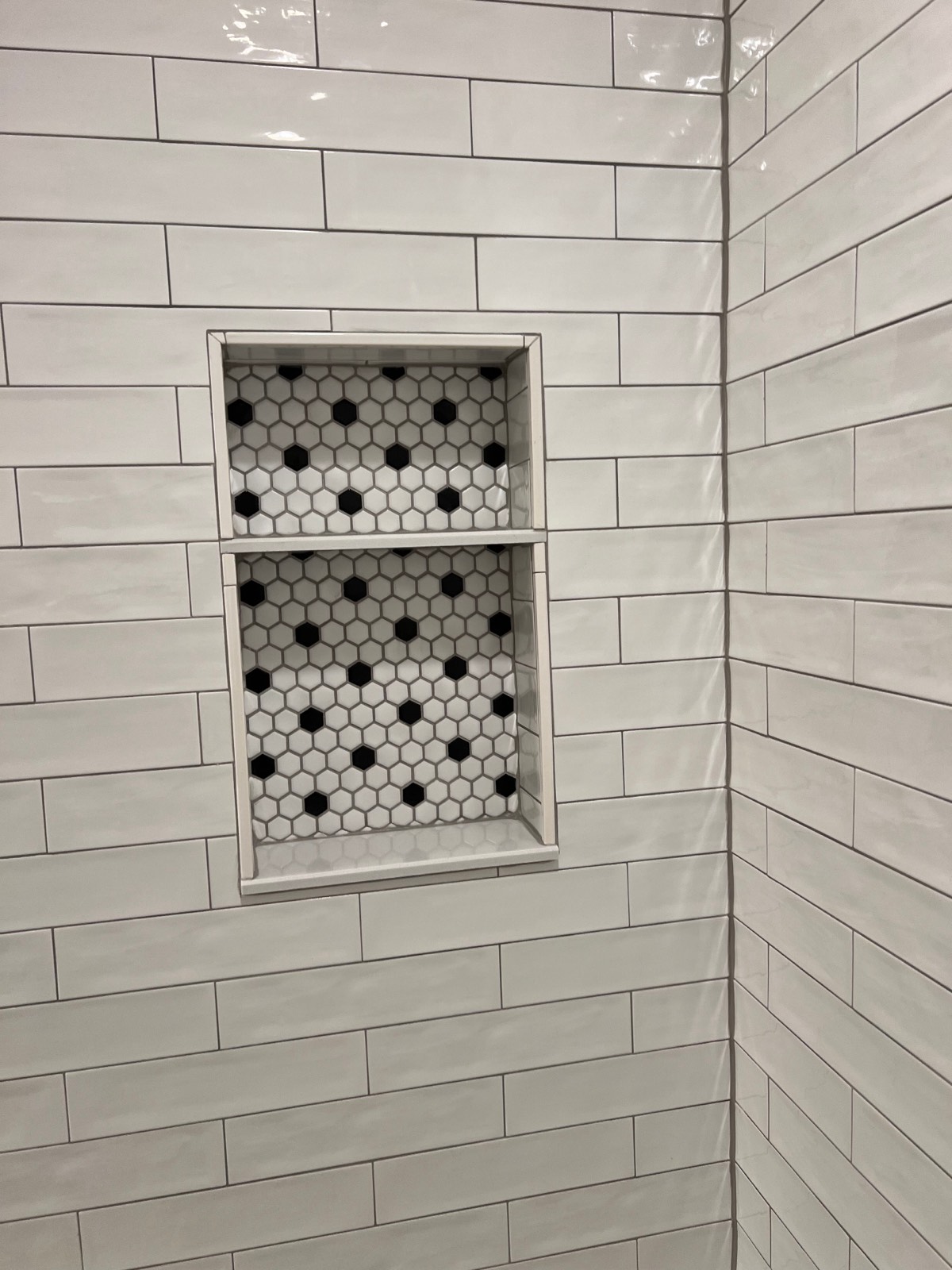 White subway tile shower wall with a hexagon mosaic niche aligned to the surrounding grout lines