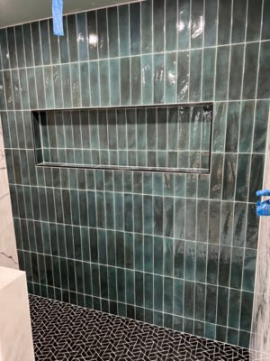 Green vertical subway tile shower with niche