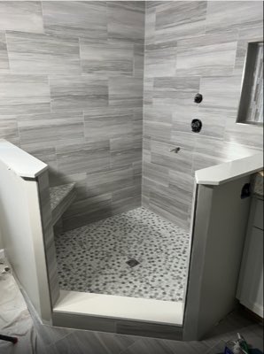 Walk-in shower with grey wood-look wall tile and pebble mosaic floor