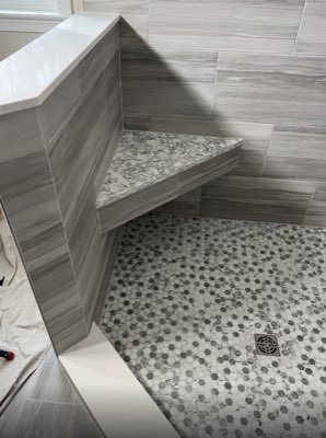 Corner shower bench with grey wood-look wall tile and hexagon mosaic floor