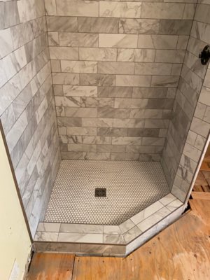 Marble-look subway tile shower with penny round floor