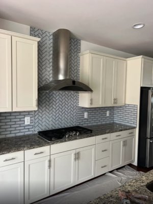 Kitchen backsplash with grey herringbone tile feature behind the range hood