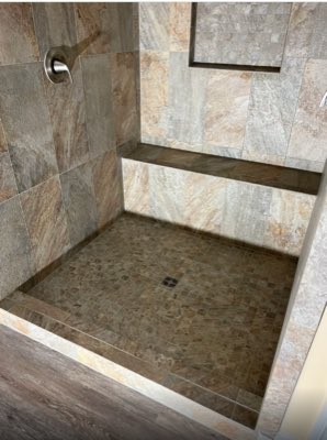 Natural stone look shower with built-in bench and mosaic tile floor