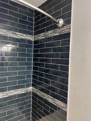 Navy blue subway tile shower with mosaic accent bands