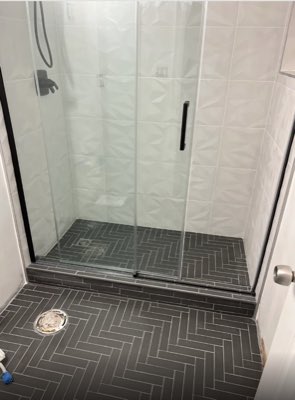 Shower with textured white 3D wall tile and grey herringbone floor